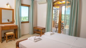 A hotel room with a bed, a desk, a chair, a mirror, and a view of the outdoors.