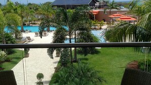 Une vue d’une zone de piscine avec des chaises longues, un bâtiment doté d’un toit végétalisé et un ciel dégagé.