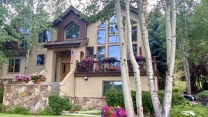 Une maison à deux étages avec des fondations en pierre, un balcon orné de jardinières et une pelouse bien entretenue.
