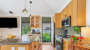 Een moderne keuken met houten kastjes, een roestvrijstalen koelkast, een magnetron en een groot kookeiland met een spoelbak.