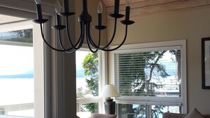Un comedor con candelabro, ventilador de techo y vistas al exterior a través de amplios ventanales.