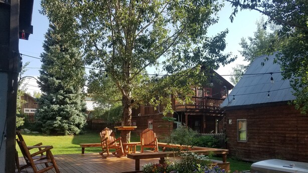 Een terras met houten meubels, een barbecue en een tuin vol bloemen.