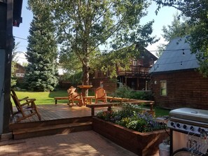 A patio with wooden furniture, a barbecue grill, and a garden area with flowers.