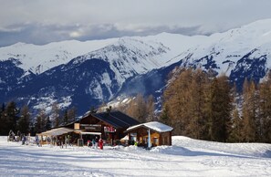 En stuga byggd av trä, med en skylt som visar texten ”Chalet Planais”, belägen i ett snötäckt bergslandskap.