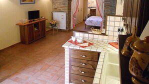 Une pièce chaleureuse avec un sol carrelé, un meuble en bois, une télévision et un mur en pierre.