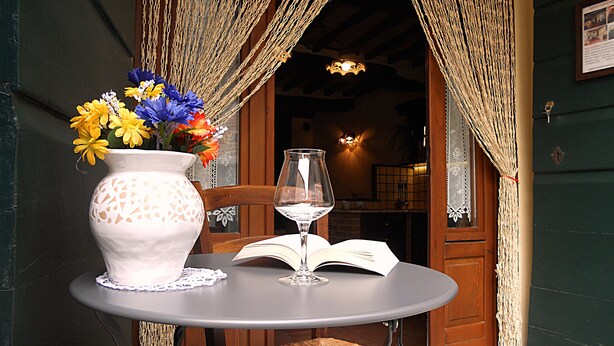 Une table avec un vase de fleurs, un verre à vin et un livre ouvert.