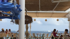 An outdoor dining area with tables and chairs, a bar area with bottles, and a view of the ocean. - Idyllic & luxury huge 7 bed / bath villa, heated pool & Jacuzzi Wifi (Xàbia)