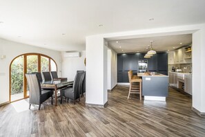 A modern kitchen with dark cabinets, a central island, and pendant lighting. - Idyllic & luxury huge 7 bed / bath villa, heated pool & Jacuzzi Wifi (Xàbia)
