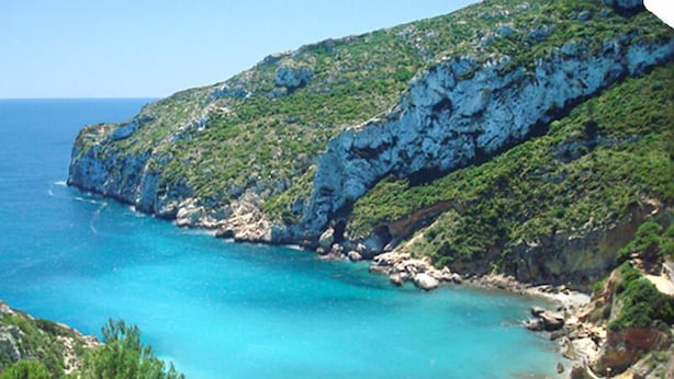 A coastal beach with clear turquoise waters, rocky cliffs, and greenery. - Idyllic & luxury huge 7 bed / bath villa, heated pool & Jacuzzi Wifi (Xàbia)