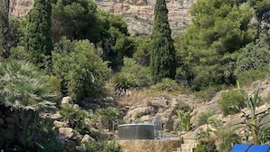 A swimming pool with clear blue water, surrounded by greenery and a rocky mountain backdrop. - Idyllic & luxury huge 7 bed / bath villa, heated pool & Jacuzzi Wifi (Xàbia)