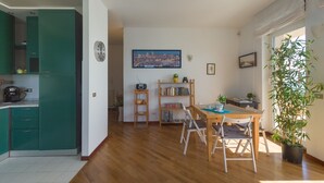A spacious living area with a wooden dining table, chairs, a bookshelf, and a large window with a view. - Amazing seaview apartment Nervi - Genova (Genova)