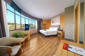 A hotel room with a bed, a desk, a chair, a TV, and a window with a view. - Dexing Hotel (Dexing)