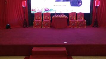 A stage with a red carpet, a table with a red tablecloth, and several chairs with red and gold patterns.