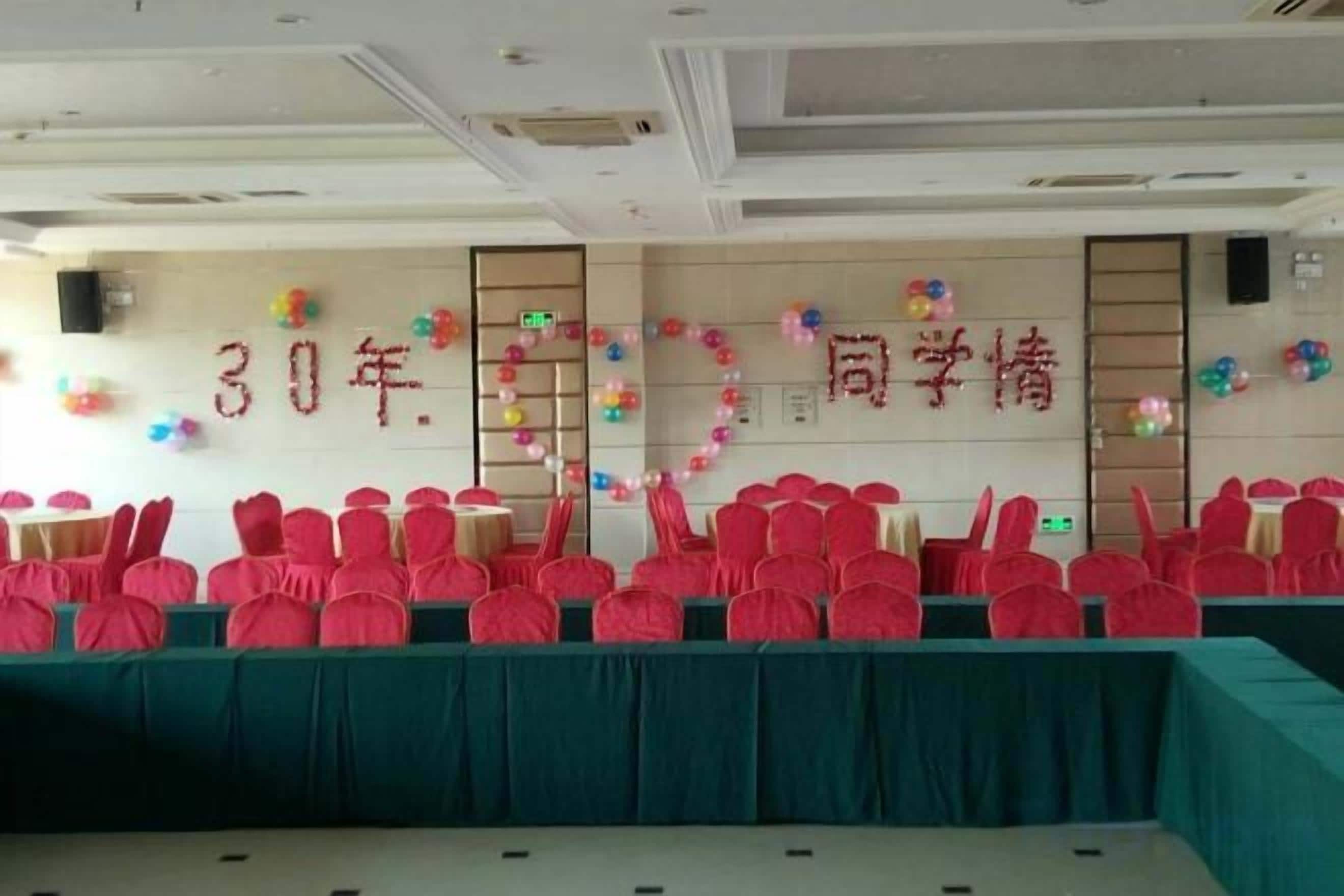 A conference room with rows of chairs, a stage, and a banner with text.