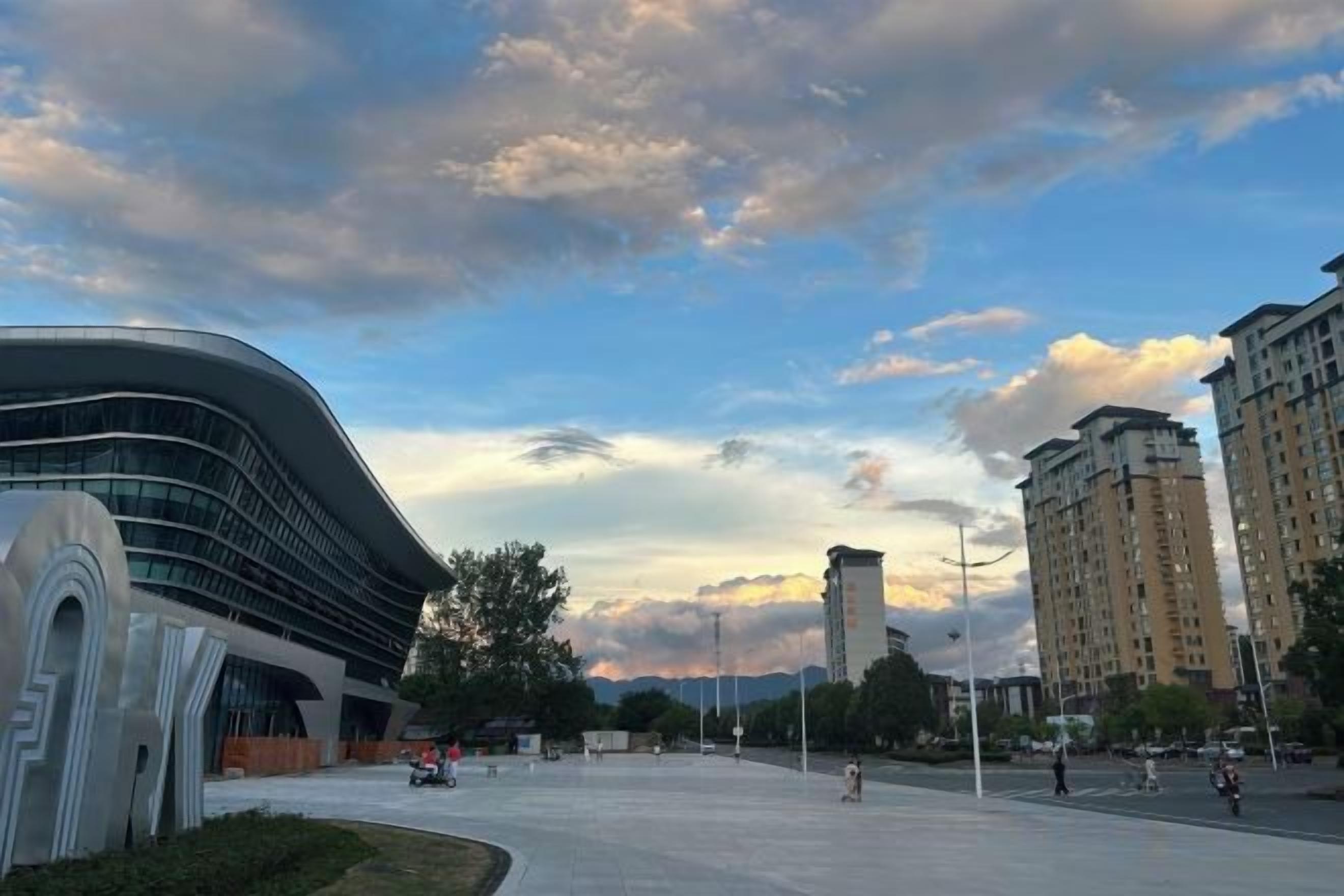 A modern building with a curved facade and a flat-roofed structure in the background.