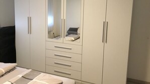 A bedroom with a large wardrobe, a bed, and a mirror. - 3-room vacation apartment, 64 square meters, with private parking in Ötlingen 79576, Weil am Rhein, near Basel/A5; accommodates up to 6 people (Weil am Rhein)