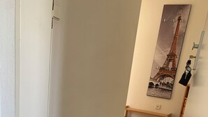 A hallway with a wooden bench, a door, and a framed picture of the Eiffel Tower on the wall. - 3-room vacation apartment, 64 square meters, with private parking in Ötlingen 79576, Weil am Rhein, near Basel/A5; accommodates up to 6 people (Weil am Rhein)