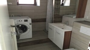 Un baño pequeño con lavadora, lavamanos y espejo.