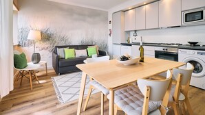 Een moderne keuken met een magnetron, fornuis en wasmachine. Er is een eethoek met een tafel en stoelen.