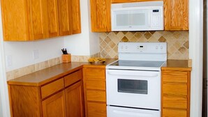 A kitchen with wooden cabinets, a white stove, and a microwave. - Red Rock House on the edge of Marsing. 2 Bedrooms 1 Bath (Marsing)