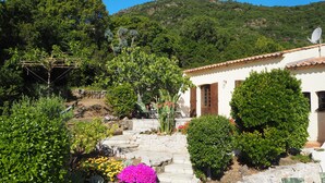 A white building with a tiled roof, surrounded by lush greenery and a stone staircase leading to a door. - Quiet holiday villa with pool and stunning sea views for up to 10 people (Cavalaire-Sur-Mer)