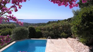 A pool with a stone deck and a view of the sea. - Quiet holiday villa with pool and stunning sea views for up to 10 people (Cavalaire-Sur-Mer)