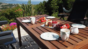 A wooden table set outdoors with plates, cutlery, and a variety of food items. - Quiet holiday villa with pool and stunning sea views for up to 10 people (Cavalaire-Sur-Mer)