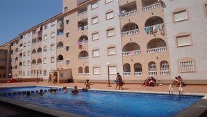 Un hôtel à plusieurs étages doté d’une piscine, de balcons avec des garde-corps et offrant une vue sur un ciel dégagé.