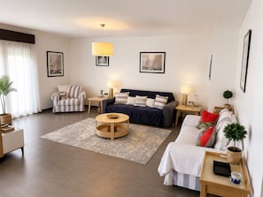 Ein modernes Wohnzimmer mit Sofa, Sessel, Couchtisch und Essbereich mit Tablett.