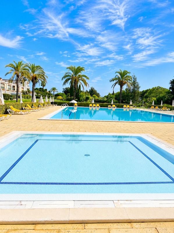 A swimming pool with lounge chairs and palm trees.