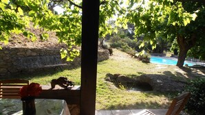 Une terrasse avec une table, des chaises et une vue sur une piscine et un jardin.