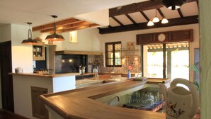 Une cuisine dotée de plans de travail en bois, de luminaires suspendus et d’une fenêtre donnant sur l’extérieur.