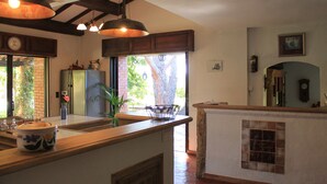 Une cuisine avec des poutres en bois, une grande fenêtre et un mur en briques.