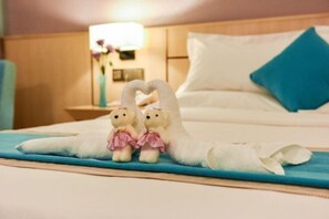 A bed with a heart-shaped towel, two teddy bears, and a blue pillow. - Maotai Yingbin Hotel (Haikou East High-speed Railway Station) (Haikou)