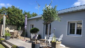 Une terrasse dotée de mobilier d’extérieur, de plantes en pot et d’un petit espace aménagé en jardin.
