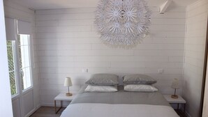 Une chambre à coucher avec un grand lit, deux tables de chevet et un luminaire décoratif au plafond.