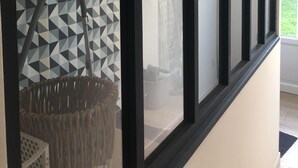 Une pièce avec un mur orné d’un motif géométrique, un luminaire suspendu et une fenêtre à cadre noir.