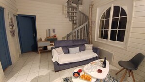 A cozy room with a sofa, a dining table with food and drinks, a chair, a staircase, and a window. - Quiet Capbreton house at the marina, between beaches and amenities (Capbreton)
