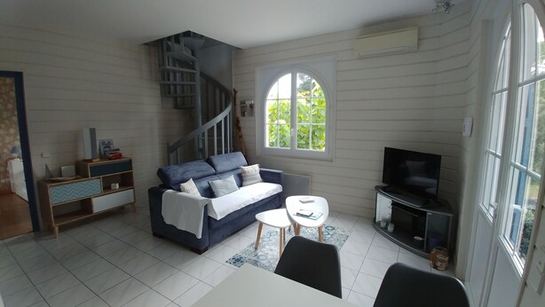 A living room with a blue sofa, a white coffee table, a TV, and a staircase. - Quiet Capbreton house at the marina, between beaches and amenities (Capbreton)