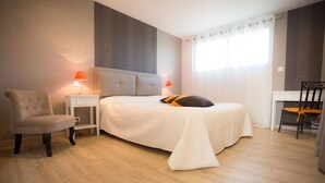 A bedroom with a bed, two bedside lamps, a chair, a desk, and a window with curtains. - Comfortable guest room "les Bruyères" in the rising sun (Bruc-Sur-Aff)