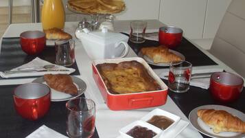 A breakfast setting with croissants, a red baking dish, and various beverages.