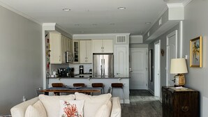 Una cocina moderna con gabinetes blancos, electrodomésticos de acero inoxidable y un comedor con mesa y sillas.