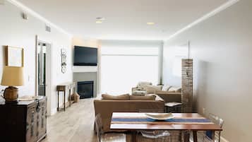 A modern living room with a fireplace, a dining area with a wooden table and metal chairs, and a sofa.