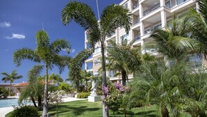 Un hotel con piscina, palmeras y una estatua en el jardín.