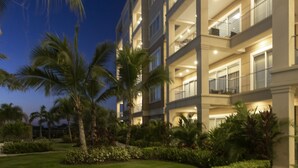 Un hotel de varios pisos con balcones, rodeado de exuberante follaje y palmeras.