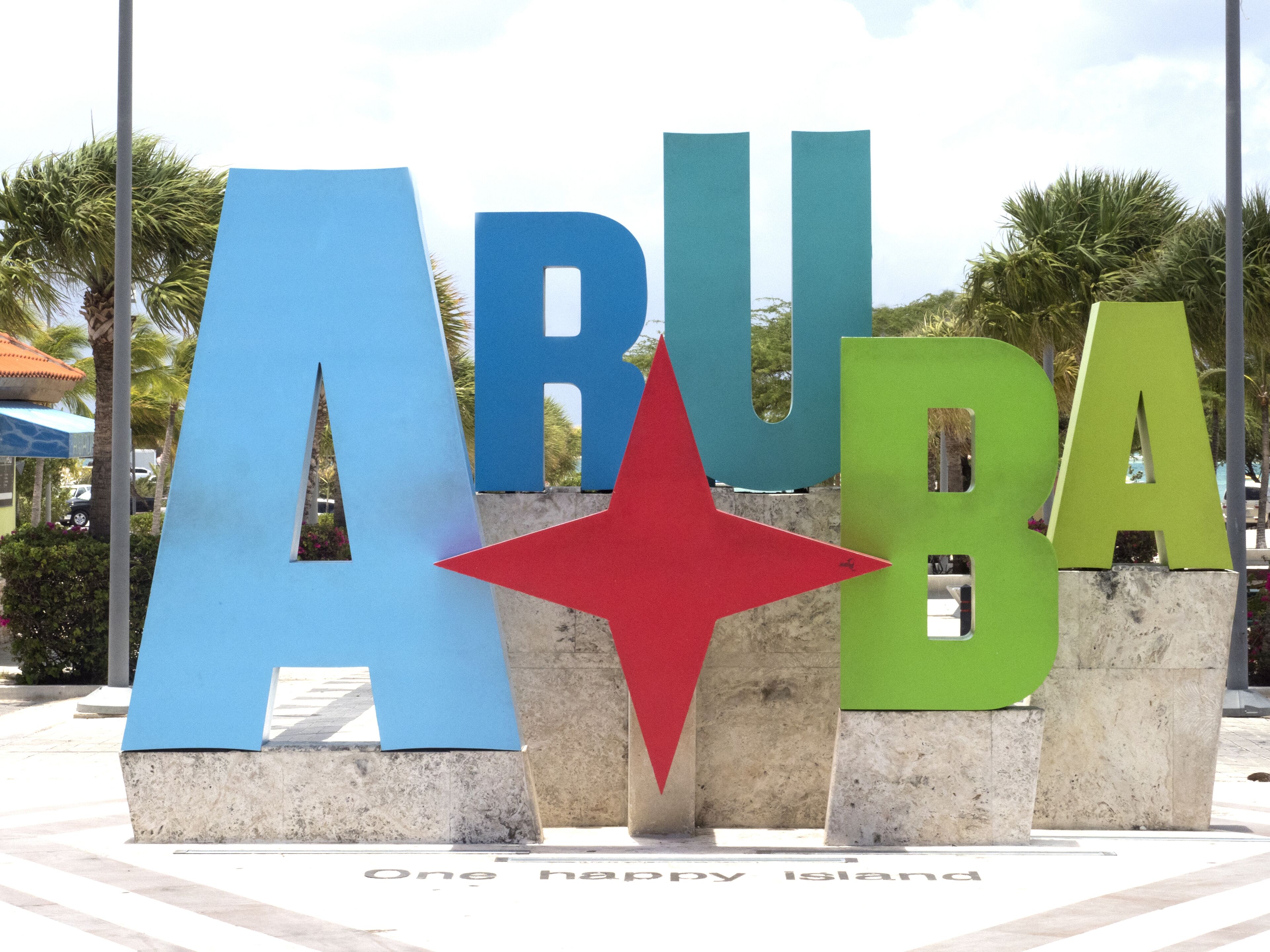 A large sign with the letters 'ARUBA' and a red star, with the phrase 'One happy island' below.