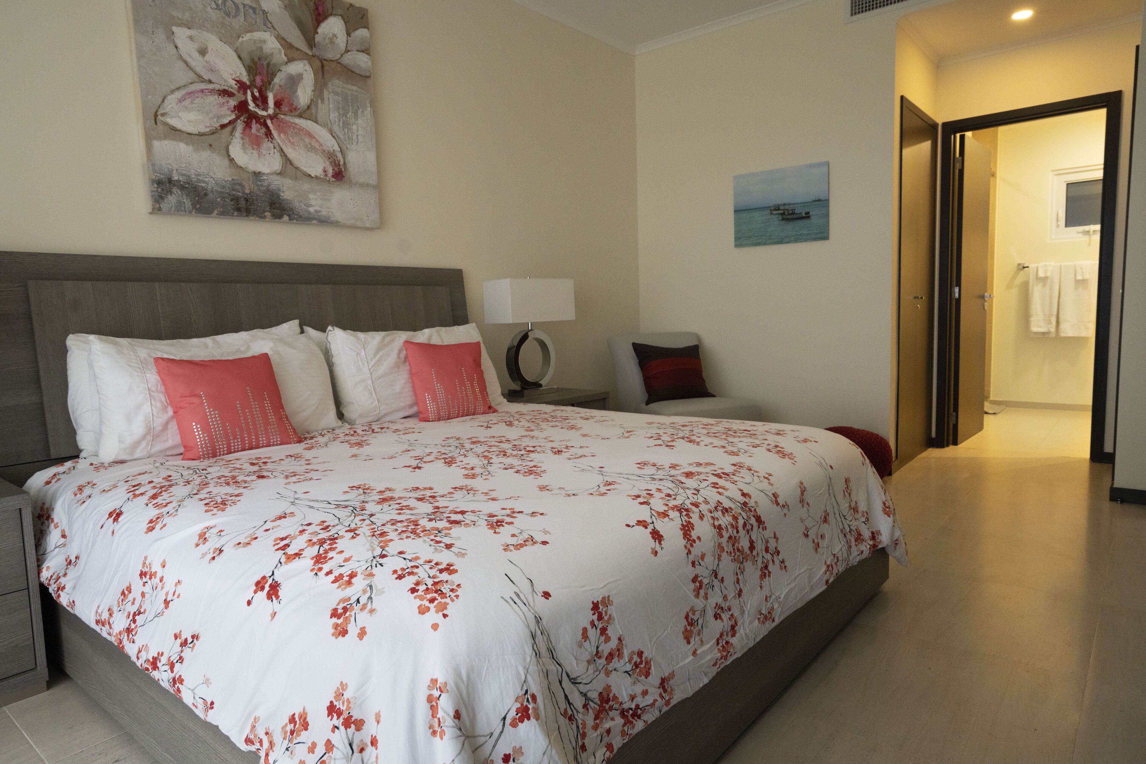 A hotel room with a large bed, a nightstand, a lamp, and a painting on the wall.