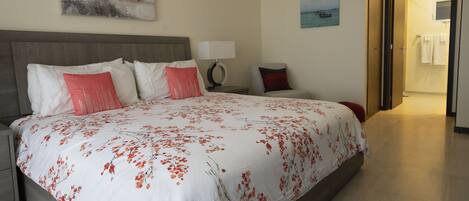 A hotel room with a large bed, a nightstand, a lamp, and a painting on the wall.