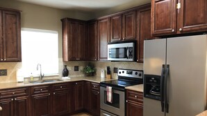 A kitchen with dark wooden cabinets, a stainless steel refrigerator, a microwave, and an oven. - 5-Star Branson Hills Villa - 4 Master Suites, Sleeps Up to 10, Pool & Golf (Branson)