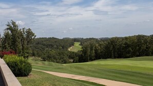 A golf course with a clear path, surrounded by trees and a distant view of a hilly landscape. - 5-Star Branson Hills Villa - 4 Master Suites, Sleeps Up to 10, Pool & Golf (Branson)